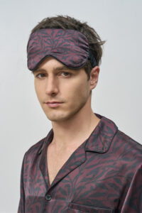 Model wears Tropical Leaves Men's Eye Mask with matching silk pajama, highlighting the delicate pattern and comfortable fit.