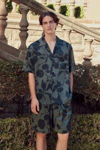 Model wears MANITO Tropical Men's Short Pajama Set in vetiver green silk with botanical print.