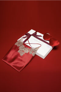 Elegant presentation of the MANITO wedding dress gift box with a red silk camisole and lace detailing, perfect for a bridal gift.