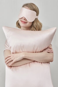 Woman wearing MANITO Wedding Mr. & Mrs. Silk Eye Mask with relaxed smile.