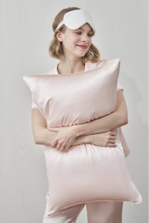 Smiling woman holding pink pillow for couples from MANITO Wedding Mr. & Mrs. Silk Pillowcases Gift Box.