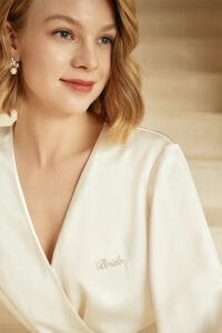 Close-up of model in white MANITO Wedding Women's Embroidered Silk Short Robe, showing the embroidered "Bride" detail.