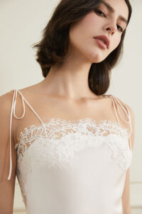A close-up of a woman wearing Windy Silk White Lace Short Dress with delicate lace detailing on the straps and neckline.