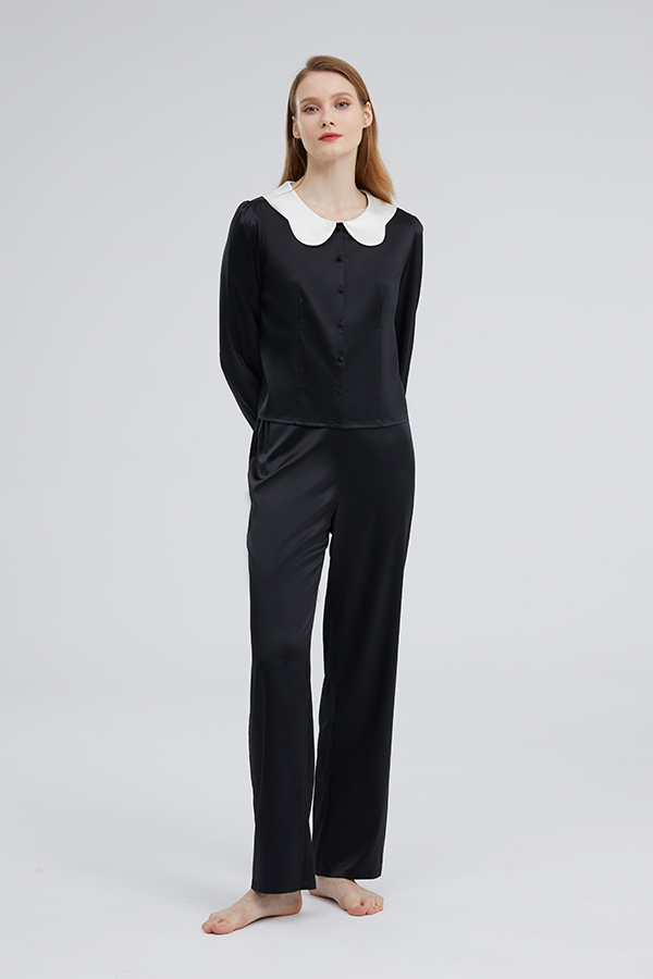 Full body view of a woman dressed in the black Doll Silk Loungewear Set, showcasing a seamless blend of luxury and casual style.