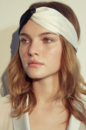 Woman wears a contrasting silk headscarf with a black and white color clash design that is fashion forward and full of personality.