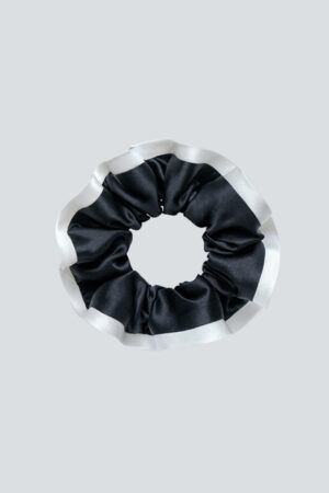 The black Two-tone Silk Scrunchie creates a sleek contrast with white ruffles and helps minimize creases during wear.