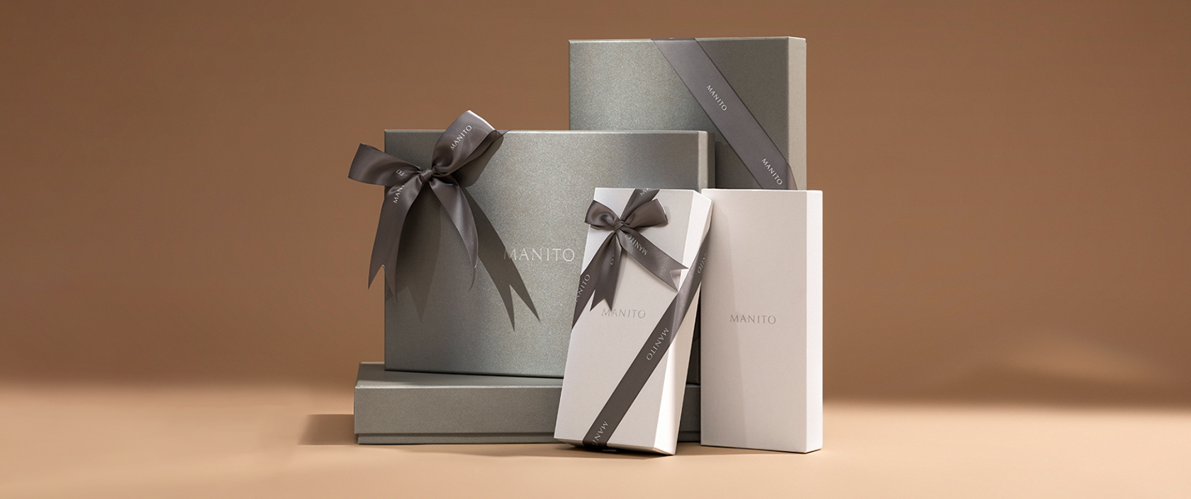 Elegant MANITO gift boxes with satin ribbons, reflecting the brand's luxurious and refined packaging