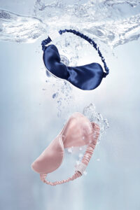 Pink and navy MANITO HA Silk Eye Masks float gracefully underwater, symbolizing deep hydration and serene relaxation.