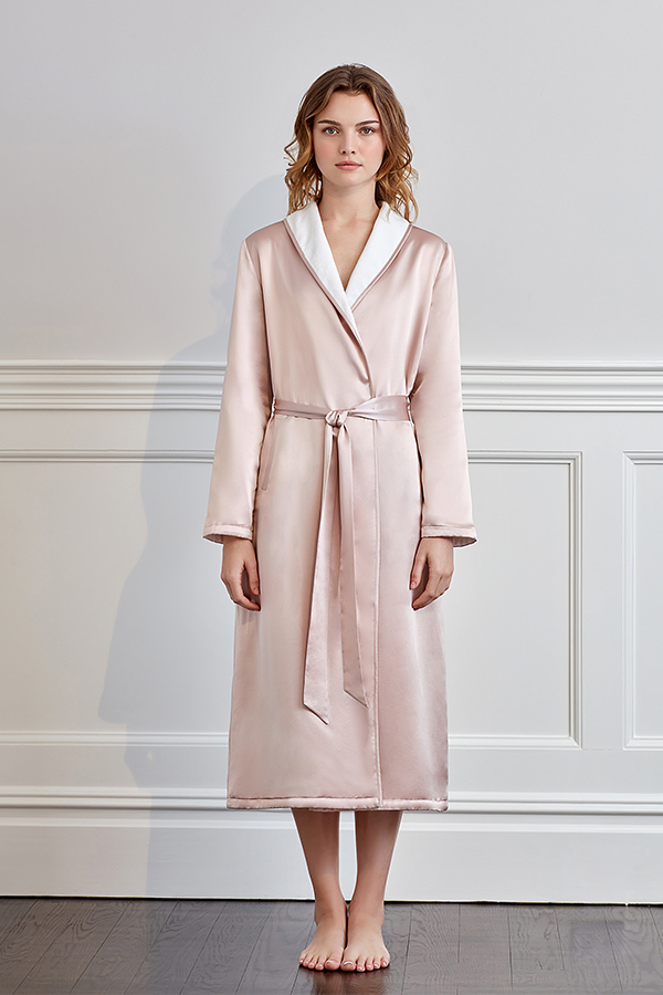 Elegant woman standing in a pink silk terry robe with contrasting white trim.