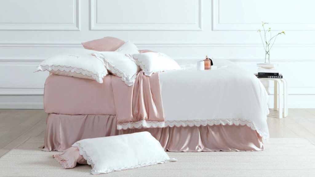 Luxurious blush pink and white silk bedding with delicate scalloped edges.