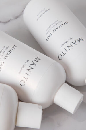 Close-up of MANITO Delicate Care Delicate Laundry Liquid Soap bottles highlighting texture and label details.