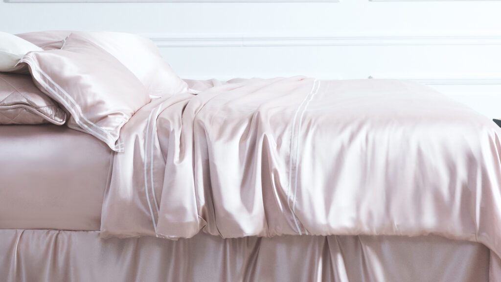 Elegant pink silk sheets draped over a luxurious bed, exuding comfort and style.