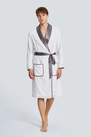 Model in white MANITO silk terry cloth robe for men with gray satin trim and belt, walking forward.
