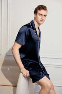 A confident man showcasing a Navy Blue Short Silk Pajama Set with white piping detail, epitomizing luxury and comfort.
