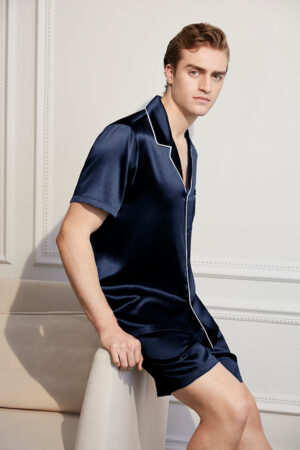 A confident man showcasing a Navy Blue Short Silk Pajama Set with white piping detail, epitomizing luxury and comfort.