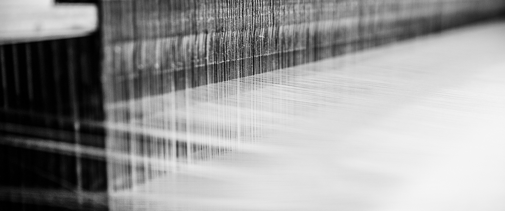 Close-up view of silk threads on a loom, detailing MANITO's expert silk weaving craftsmanship.