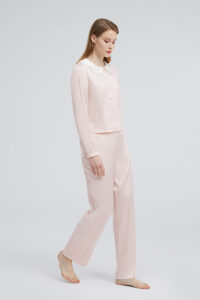 Woman in a pink Doll Silk Loungewear Set, the soft hue complementing the relaxed yet luxurious design.