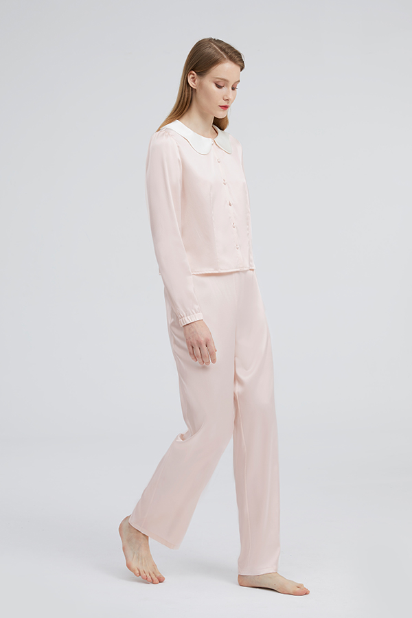 Woman in a pink Doll Silk Loungewear Set, the soft hue complementing the relaxed yet luxurious design.