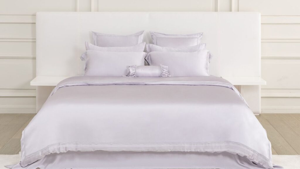 King-size lavender silk sheets fitting snugly on a queen-size bed highlight silk bedding benefits.