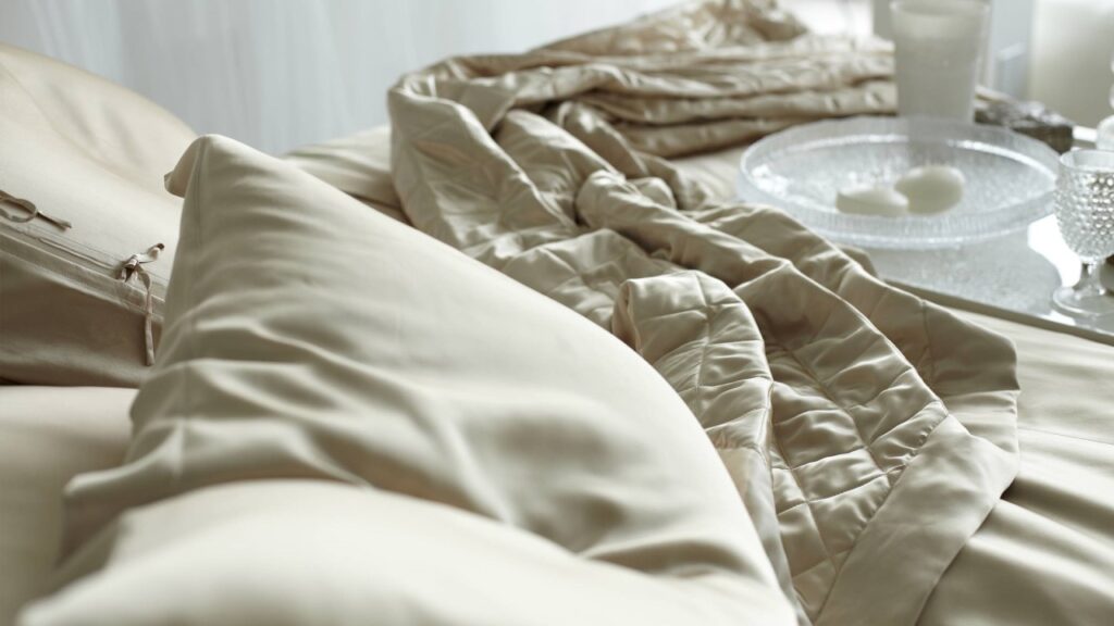 Luxurious silk bedding set on a neatly made bed, potential remedy for insomnia