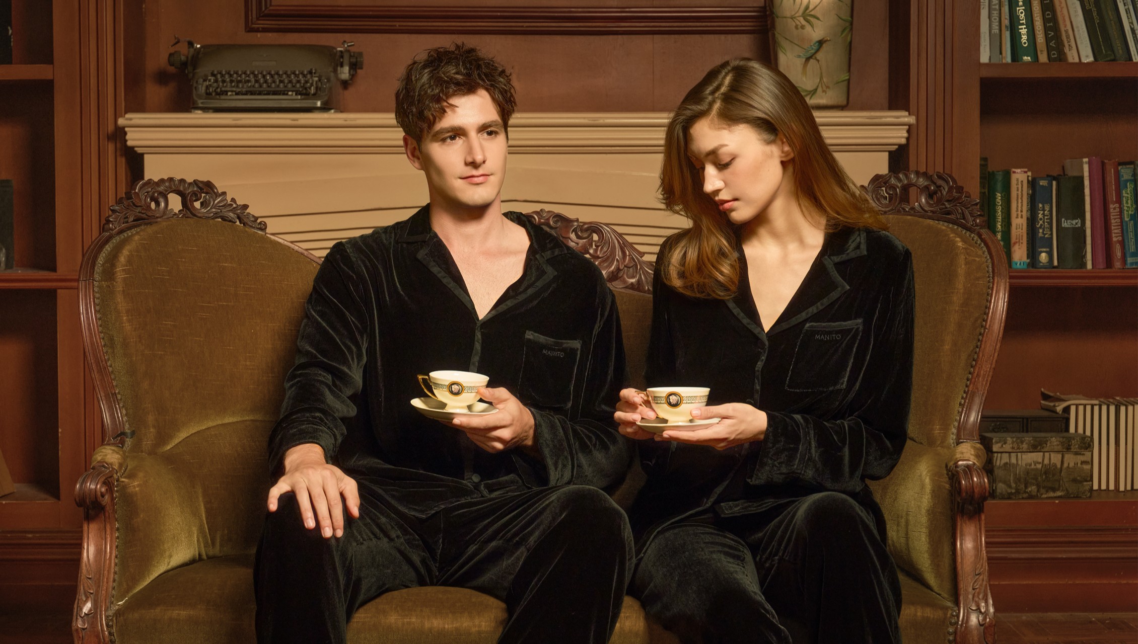 A couple relaxing in matching velvet pajamas, enjoying a moment of luxurious comfort.