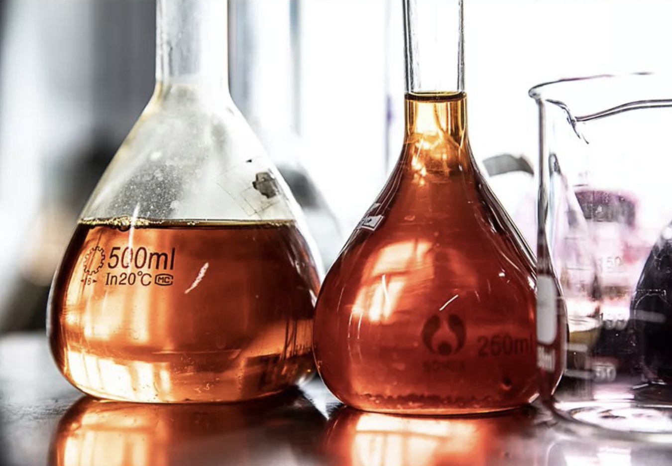 Two glass flasks with amber solutions, marked for quality testing, demonstrating the brand's commitment to excellence.