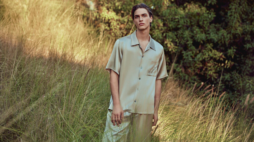 Man wearing silk pajamas standing in tall grass