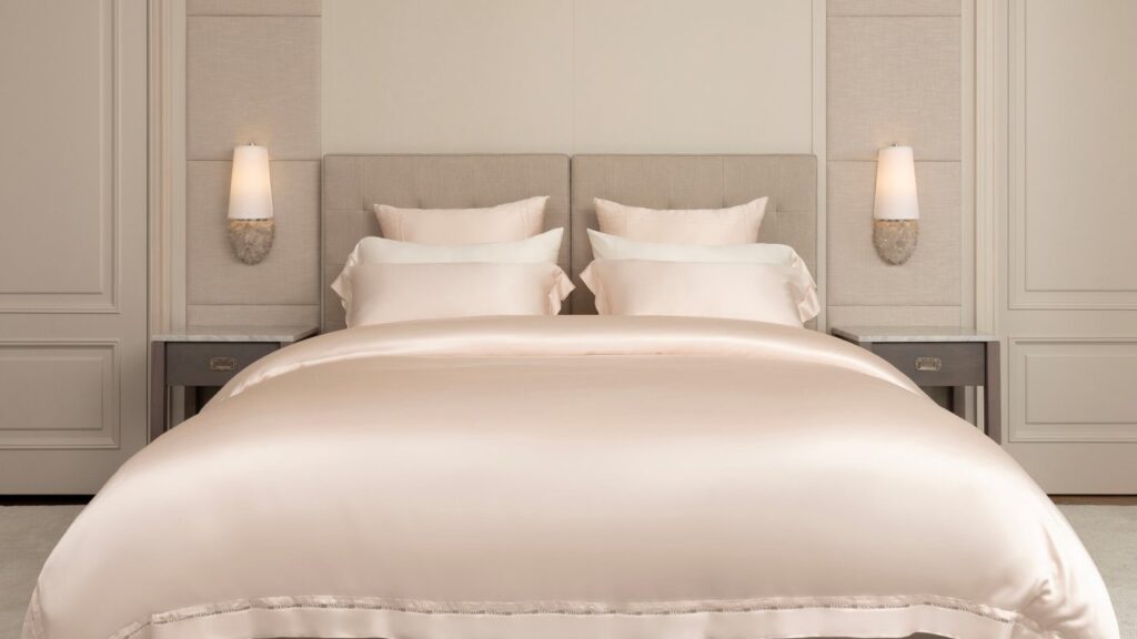 Elegant beige silk sheets on a neatly made bed, hypoallergenic and gentle for baby's skin.