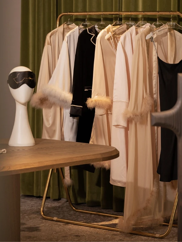 MANITO silk loungewear with feather trim and constellation eye mask displayed in a cozy boutique setting.