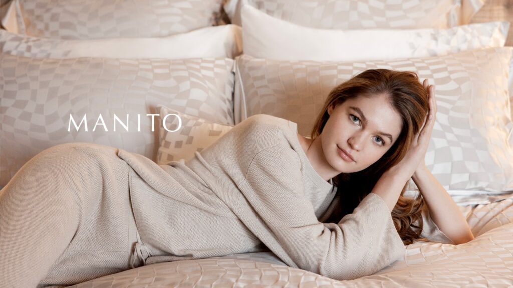 A woman relaxing on a bed with silk bedding, wearing cozy silk loungewear.