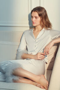MANITO Diva Feather Trimmed Pajama Set in ivory white displayed in a soft indoor light on a cream sofa.