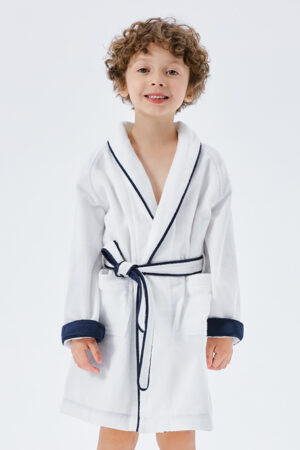 Cheerful curly-haired child in a white silk terry robe with navy trim and tie.