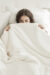 Elegant woman peeking out from a silk-filled duvet, showcasing comfort and luxury.