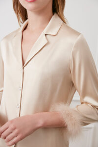 Close-up of champagne MANITO Diva Pajama top with feather-trimmed cuffs and crystal buttons.