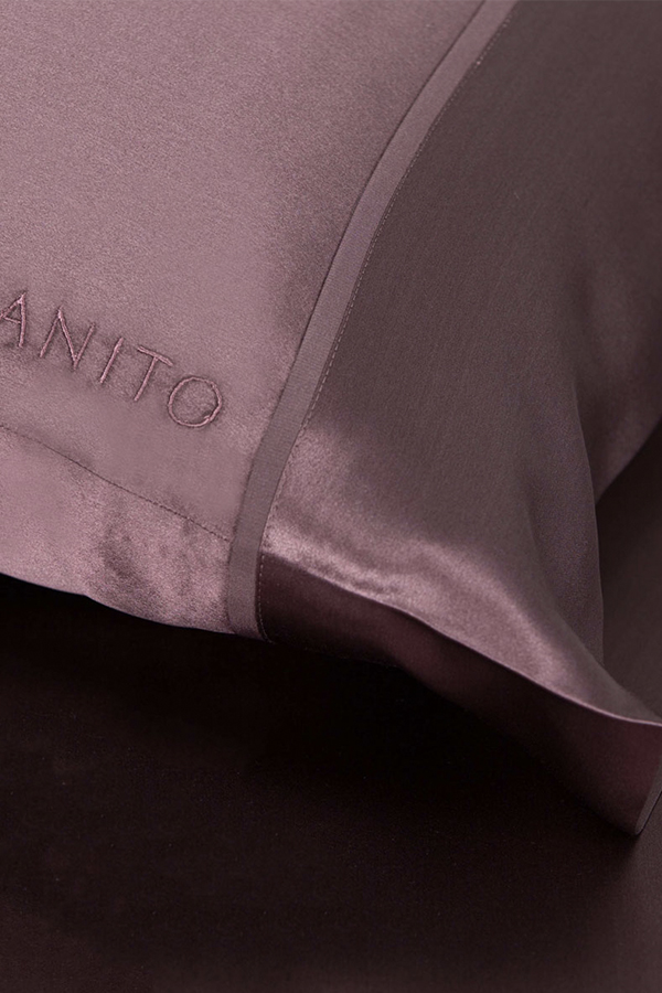 Close-up of The 22 Silk Pillowcase Set in plum purple color with embroidered logo of MANITO.