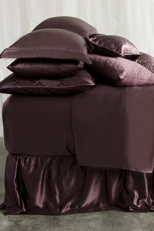 Luxurious 22 momme silk bedding set in a plum purple color with quilted pillows and silk bedskirt.
