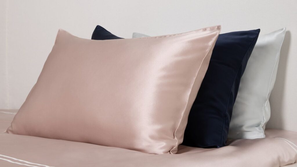 Elegant silk pillowcases on a bed, highlighting the luxurious feel and benefits for acne-prone skin.