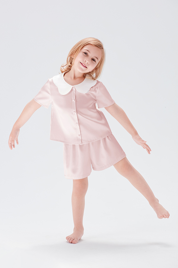 Little girl smiling in Doll Kid's Short Pajama Set with peter pan collar in ballet pink.