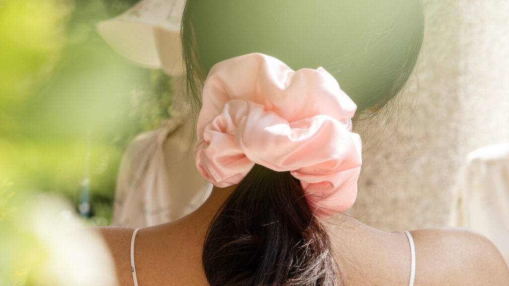Woman wearing a light pink silk scrunchie in her hair