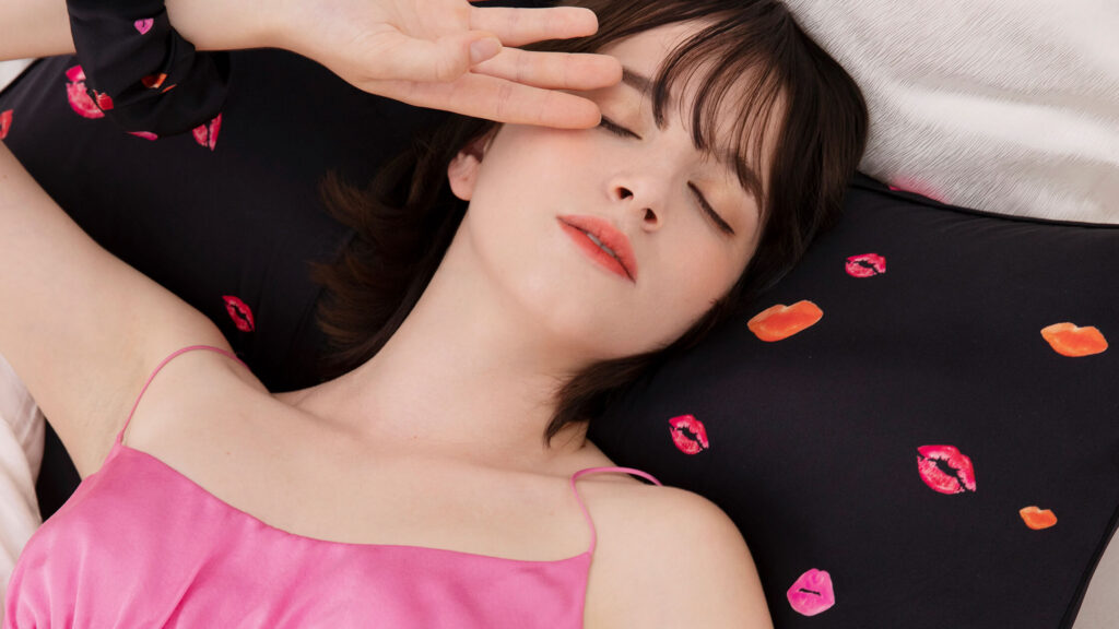 Young woman sleeping peacefully on a black silk pillowcase, demonstrating silk's benefits for preventing acne.