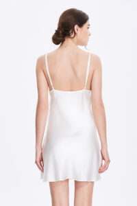 Back view of a woman wearing a white Essential Silk Slip Dress, showcasing the dress's sleek silhouette.