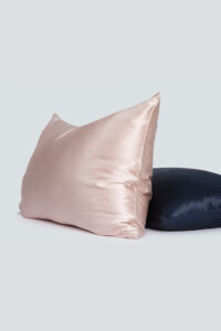 Two silk pillowcases in elegant soft pink and navy blue, showcasing sheen and luxury.