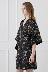 Model inside wearing a black Lrisette Silk Short Kimono with vibrant floral prints.