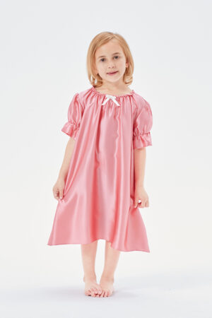 Sweet little girl standing in a peach pink Shirley silk nightgown with puffed sleeves.