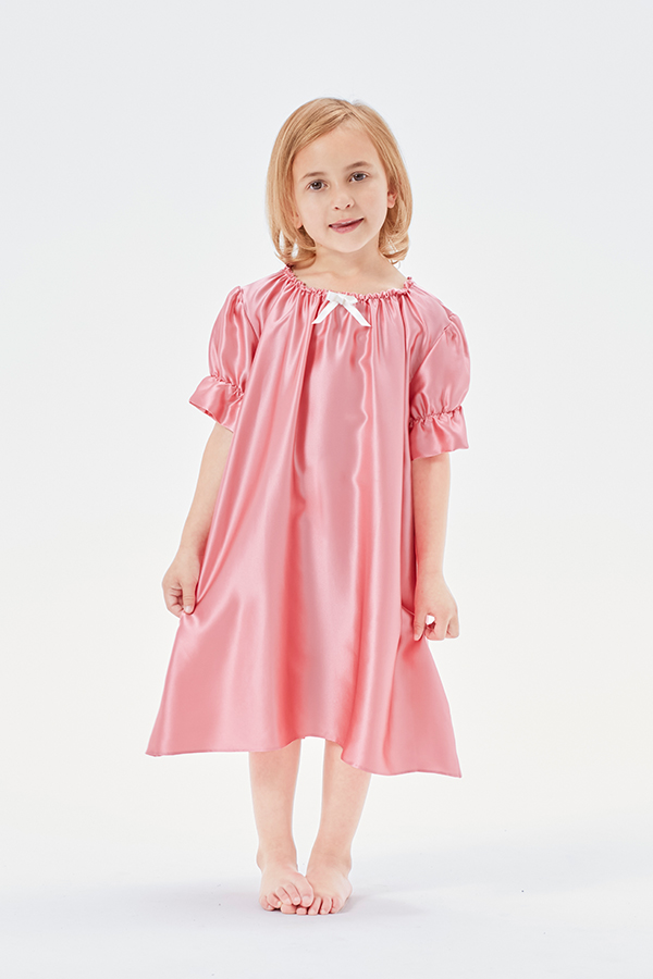 Sweet little girl standing in a peach pink Shirley silk nightgown with puffed sleeves.