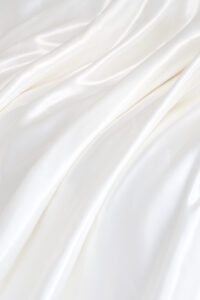Close-up of Gleam Silk Quilt, smooth white silk surface falling in soft folds for a cloud-like feel.
