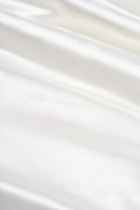 Detail of Gleam Silk Quilt jacquard, with "Silk Moments" subtly woven into the luminous white silk.