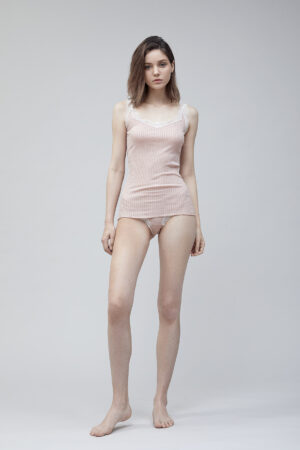 Woman posing in a soft pink Knitting Silk Camisole Top with delicate lace detailing on the edges.